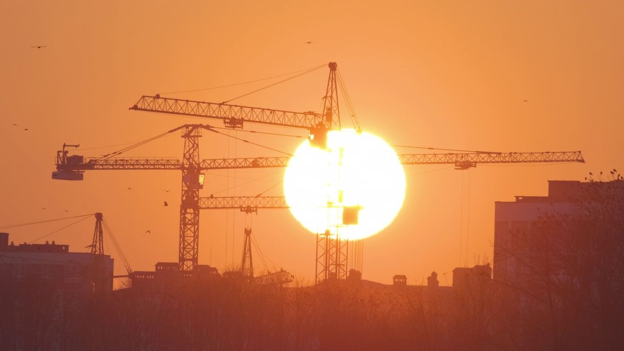 夕阳下高楼公寓建筑工地塔吊的黑色剪影。房地产开发视频素材