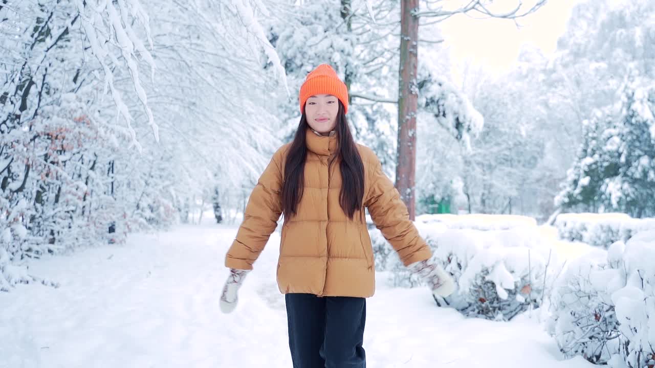 快乐快乐的年轻女子跳舞，快乐地跑下公园雪冬天寒冷的天气。幸福。亚洲女学生在雪地上微笑着跳着走。快乐,视频素材