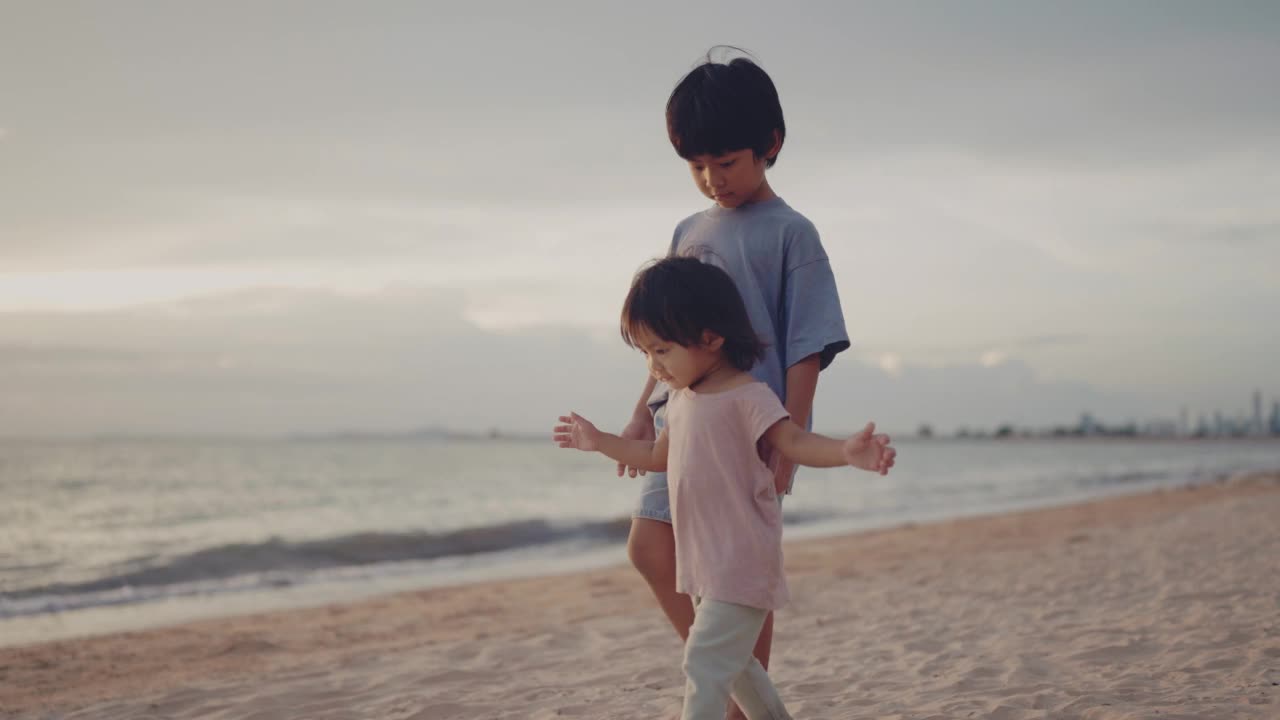 亚洲小男孩和小女孩在沙滩上奔跑玩耍。视频素材