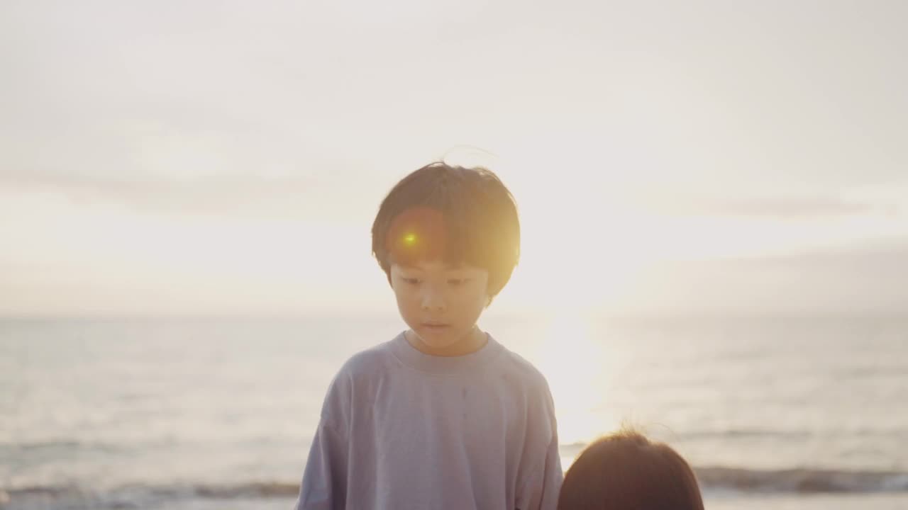 亚洲小男孩和小女孩在沙滩上奔跑玩耍。视频素材