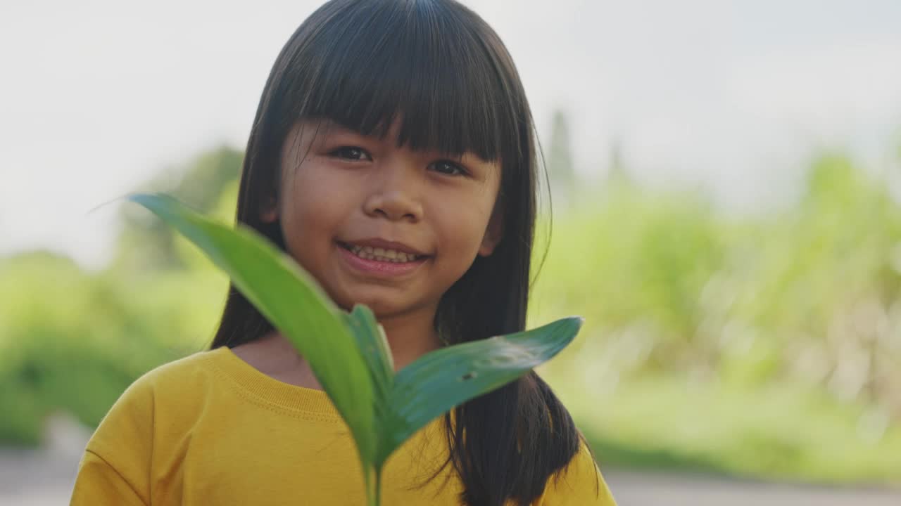 小亚洲女孩手里拿着小植物。视频素材