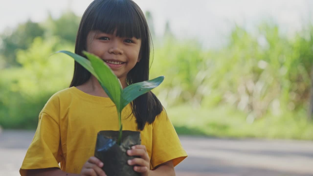 小亚洲女孩手里拿着小植物。视频素材