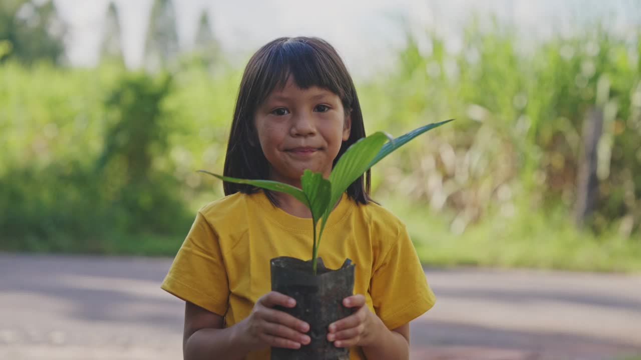 小亚洲女孩手里拿着小植物。视频素材