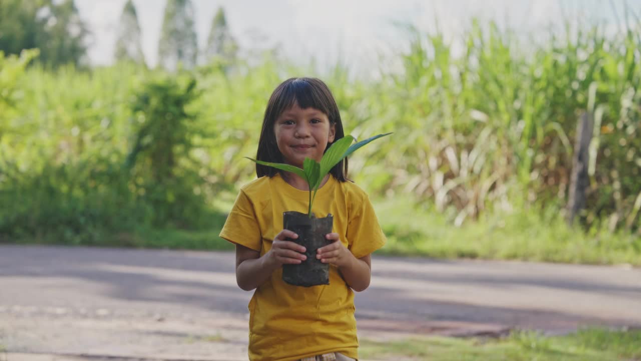 小亚洲女孩手里拿着小植物。视频素材