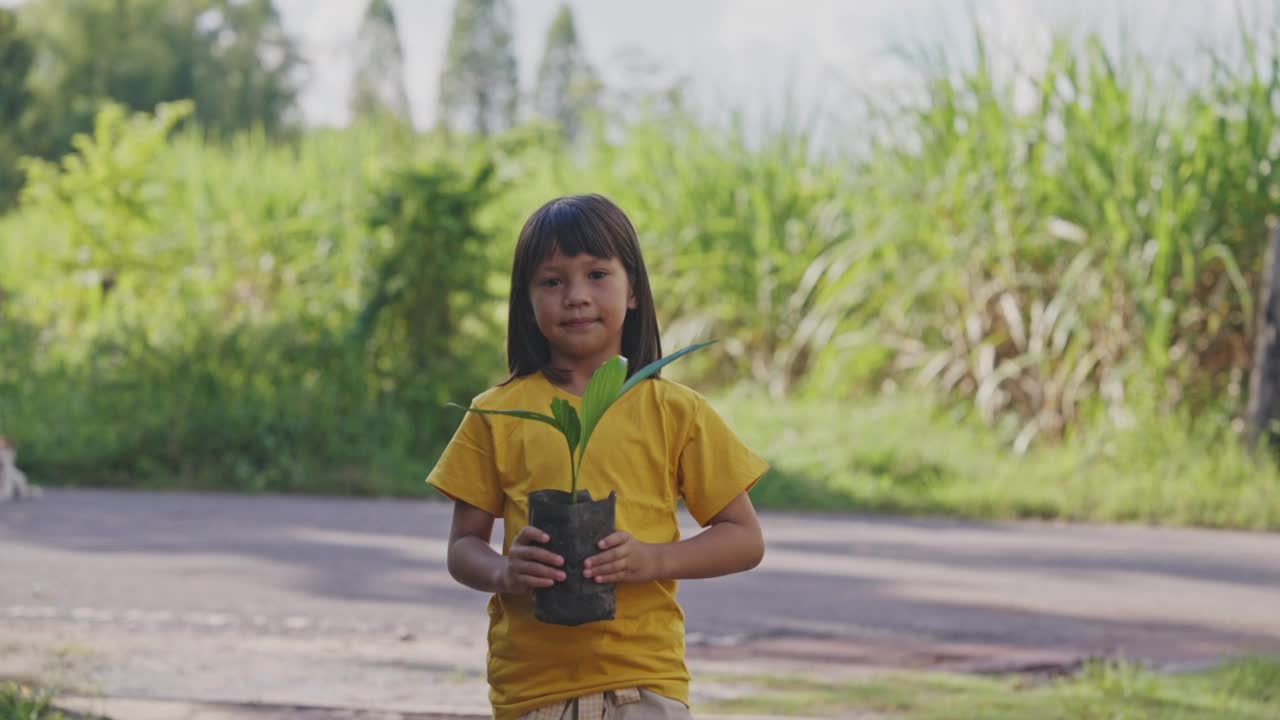 小亚洲女孩手里拿着小植物。视频素材