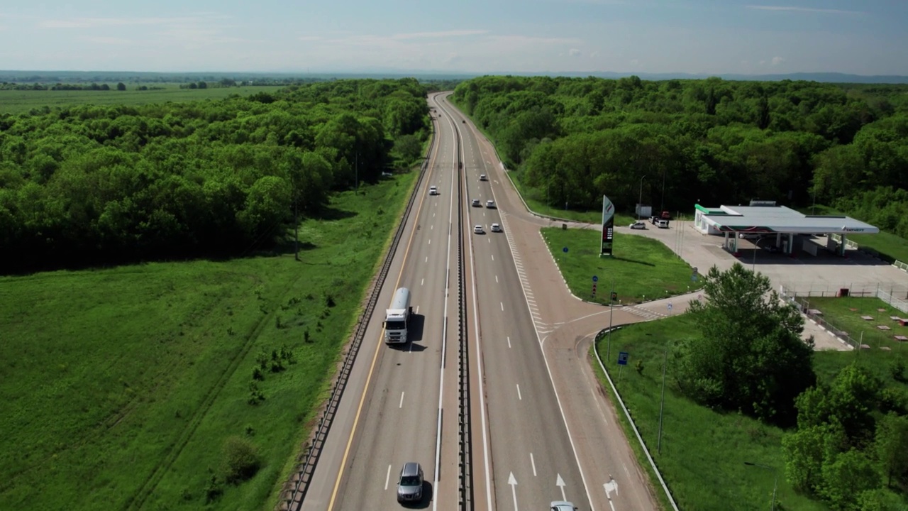 在高速城际公路上的空中飞行，车辆在公路上行驶。夏天阳光明媚的一天，附近有森林和农村的田野视频下载