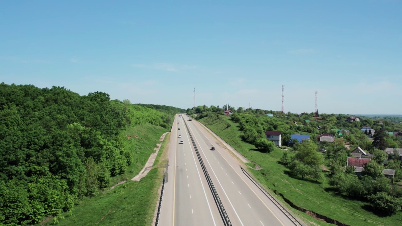 在高速城际公路上的空中飞行，车辆在公路上行驶。夏天阳光明媚的一天，附近有森林和农村的田野视频下载