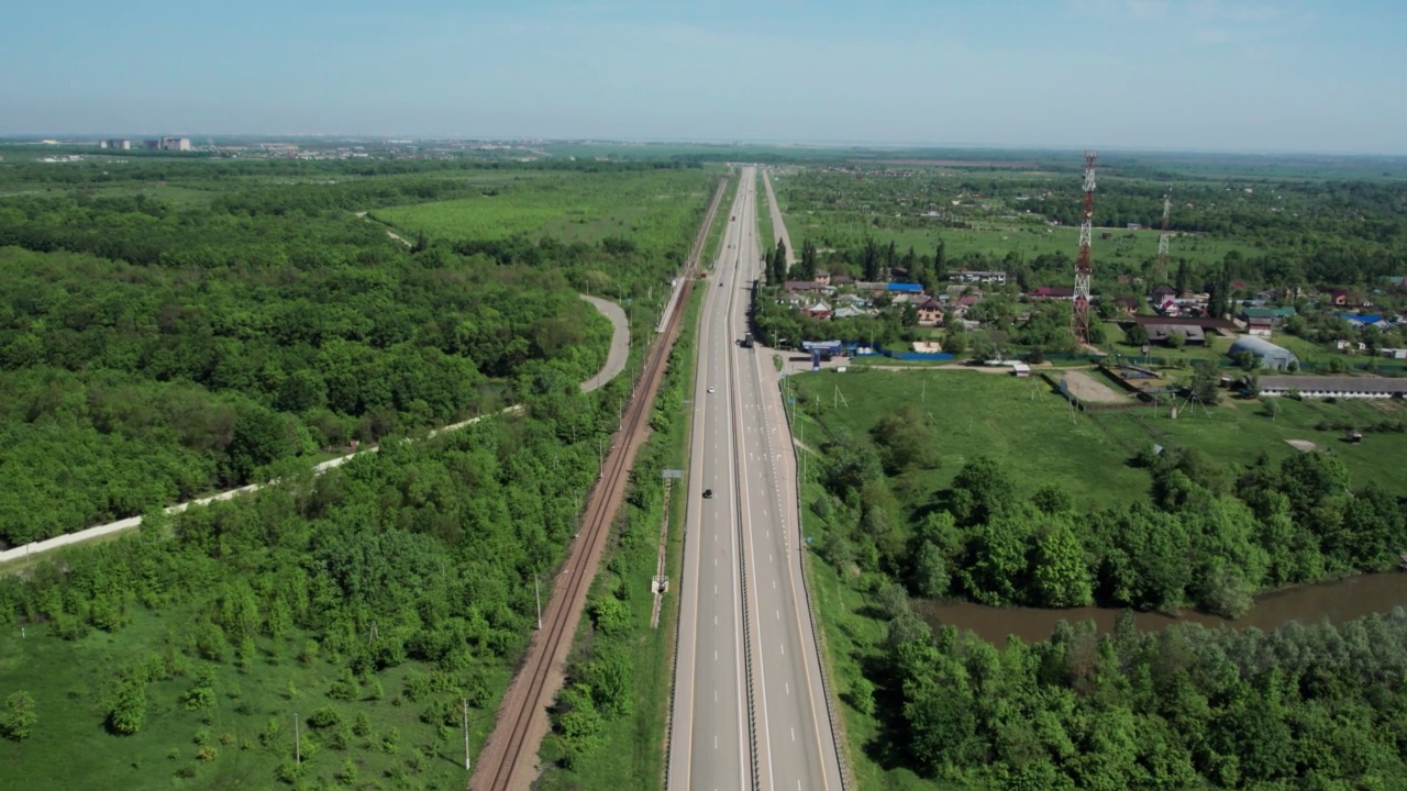 在高速城际公路上的空中飞行，车辆在公路上行驶。夏天阳光明媚的一天，附近有森林和农村的田野视频素材