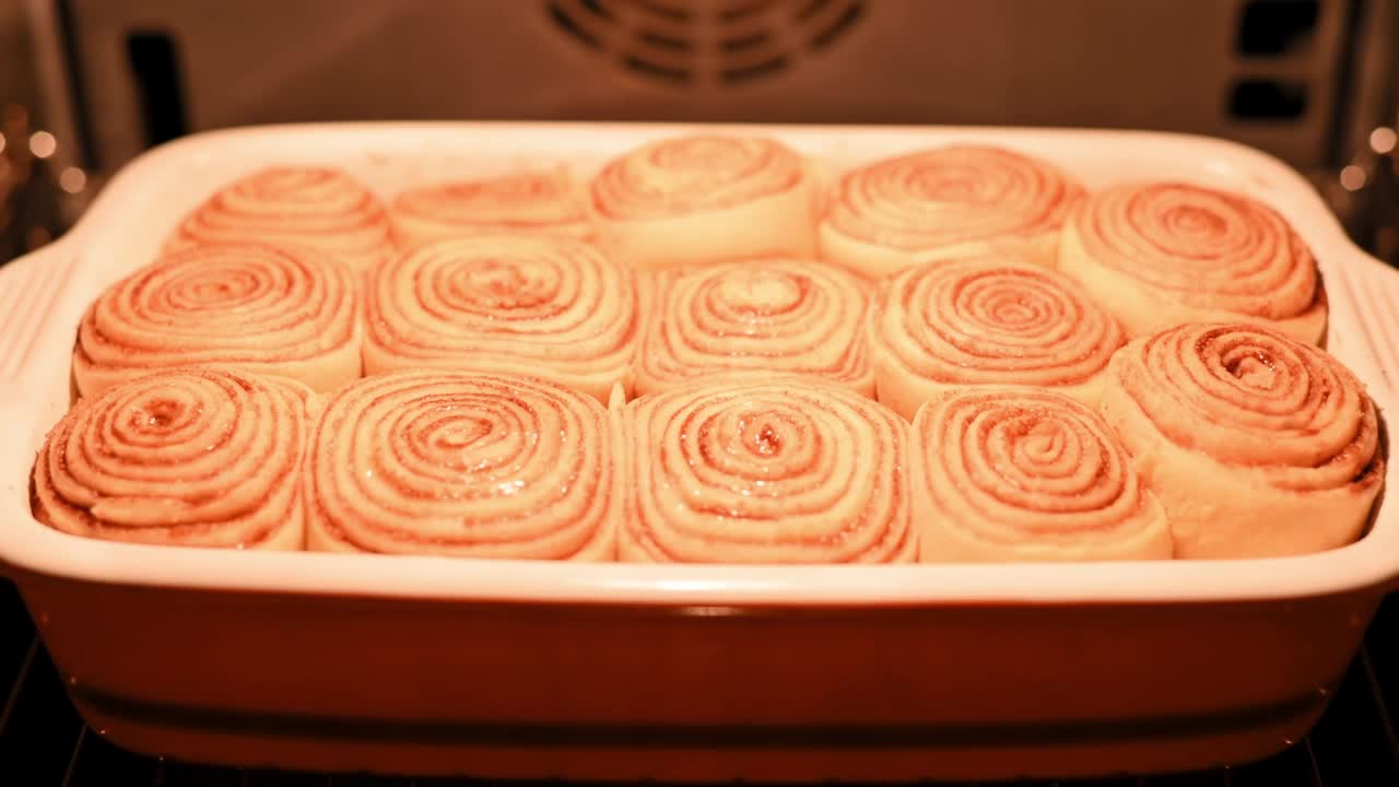 肉桂卷。肉桂自制面包是在烤箱里烤的。自制肉桂包的过程，酥皮香可口，烘焙产品。新鲜的烘焙，甜甜的传统甜点视频素材