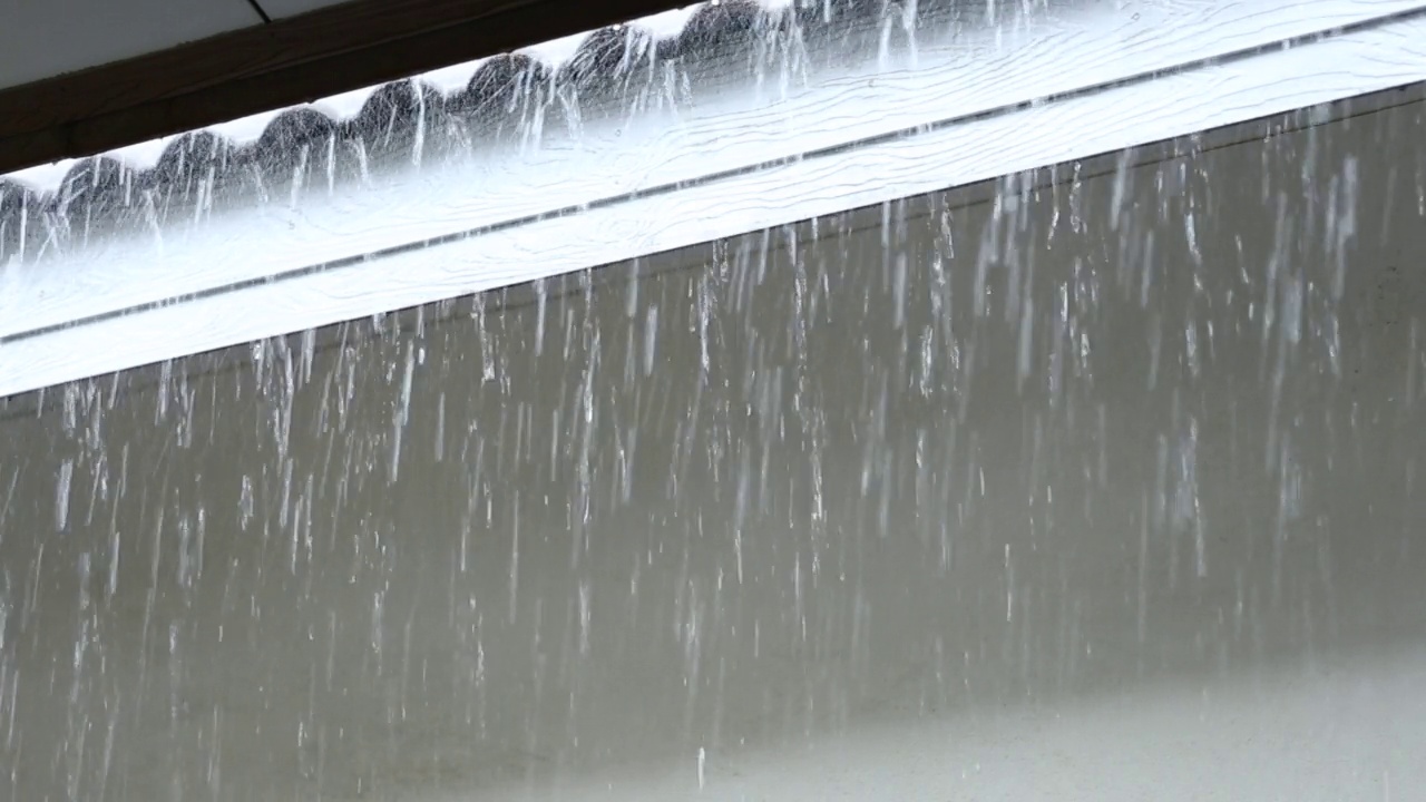 天在下雨，雨水从屋顶上倾泻而下。视频素材