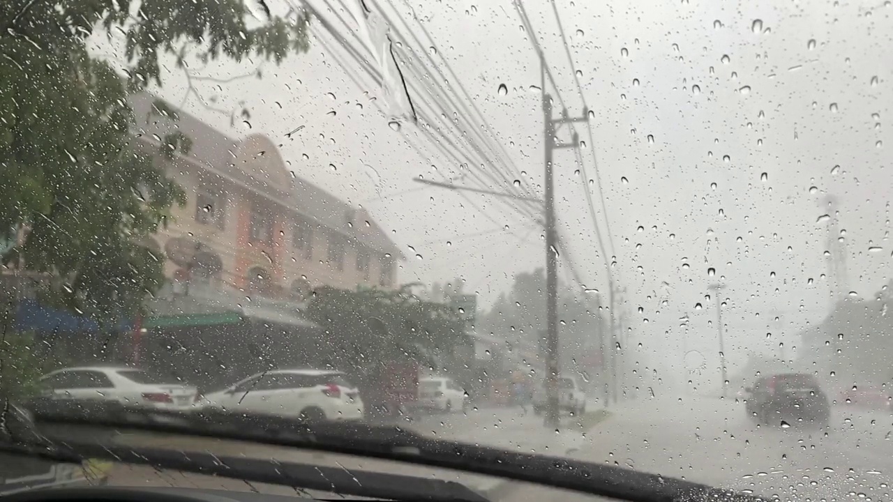 雨刷在工作，雨水落在一辆汽车的挡风玻璃上，泰国的雨季。视频下载