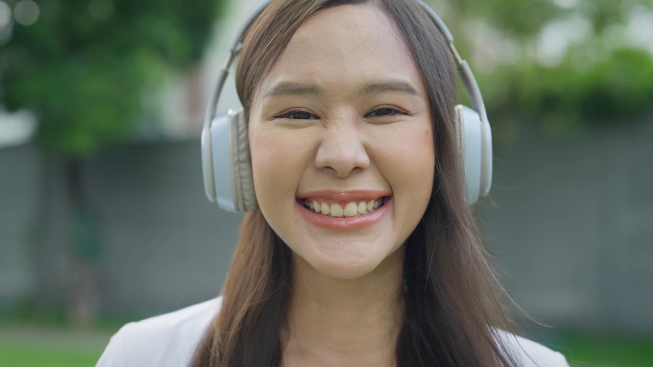 美丽的亚洲女人在大自然中享受着优美的音乐。视频素材