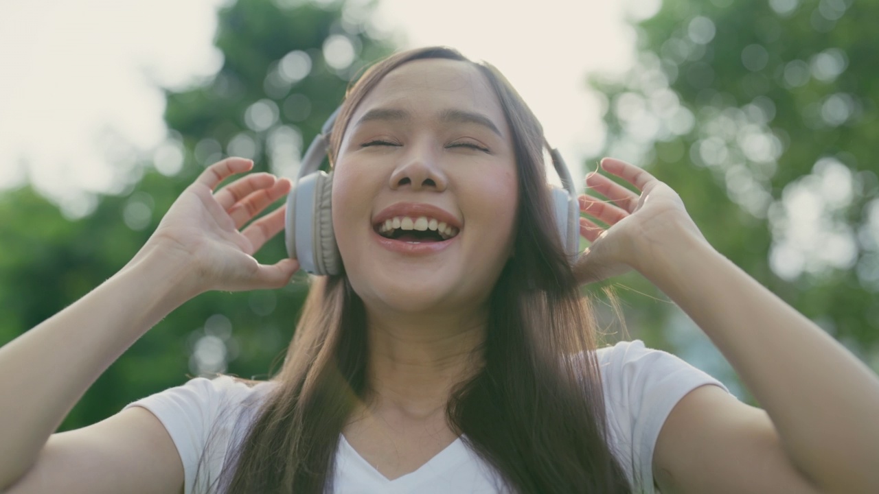 美丽的亚洲女人在大自然中享受着优美的音乐。视频素材