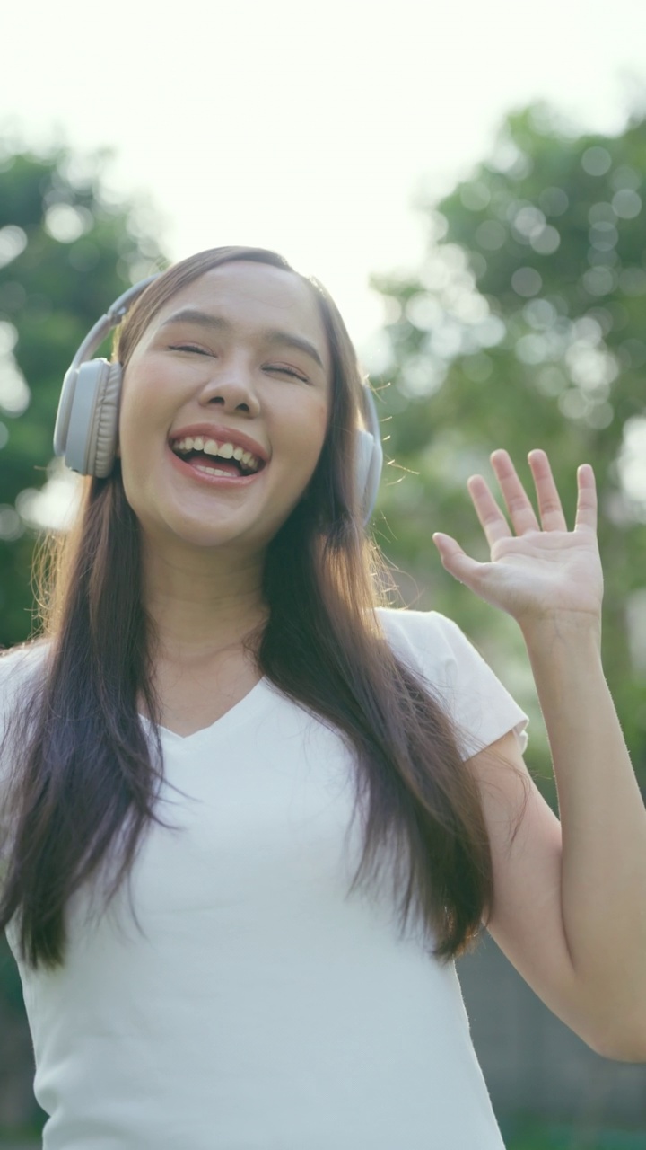 美丽的亚洲女人在大自然中享受着优美的音乐。视频素材