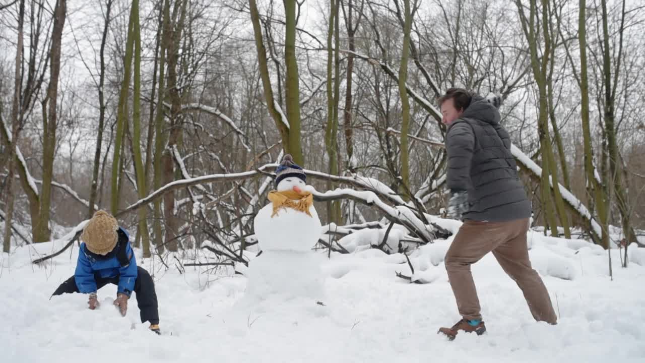 成熟的父亲和他的儿子在冬天的森林里打雪仗。爸爸和孩子一起玩，一起度过美好的时光。视频素材