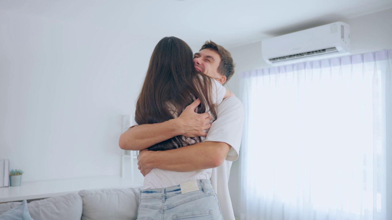 白人青年男女在家里的客厅里互相拥抱。迷人浪漫的新婚夫妇男女花时间一起在家里庆祝周年纪念日和情人节。视频素材