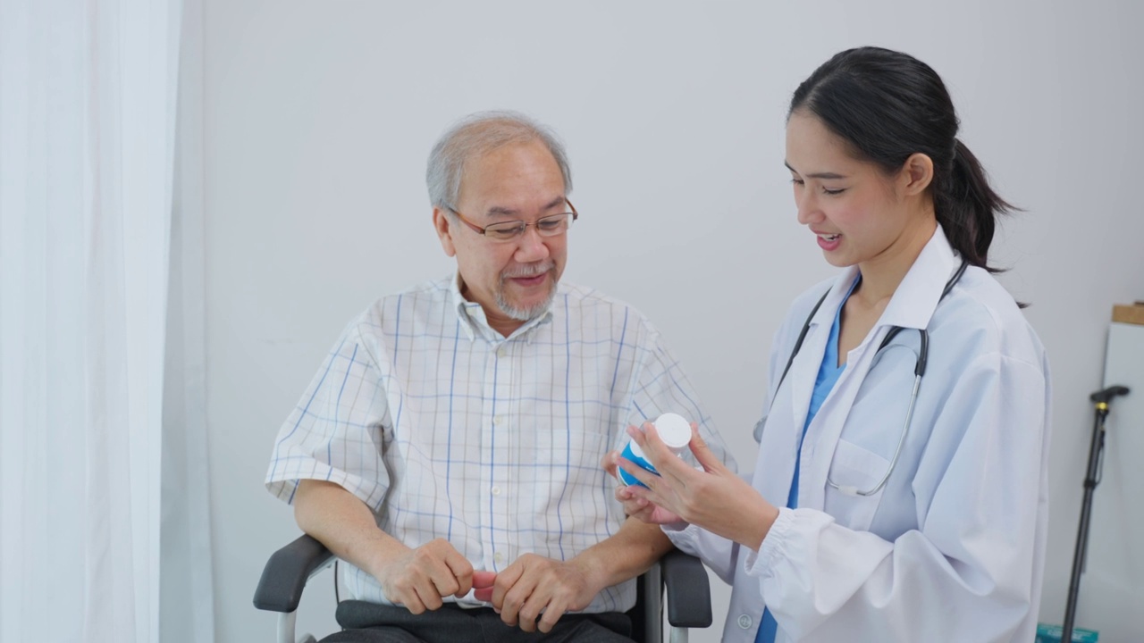 亚洲老年男性患者在敬老院与医生护士会诊。护理治疗师药剂师女孩拿着药瓶，在家里的客厅里给老人解释处方。视频素材