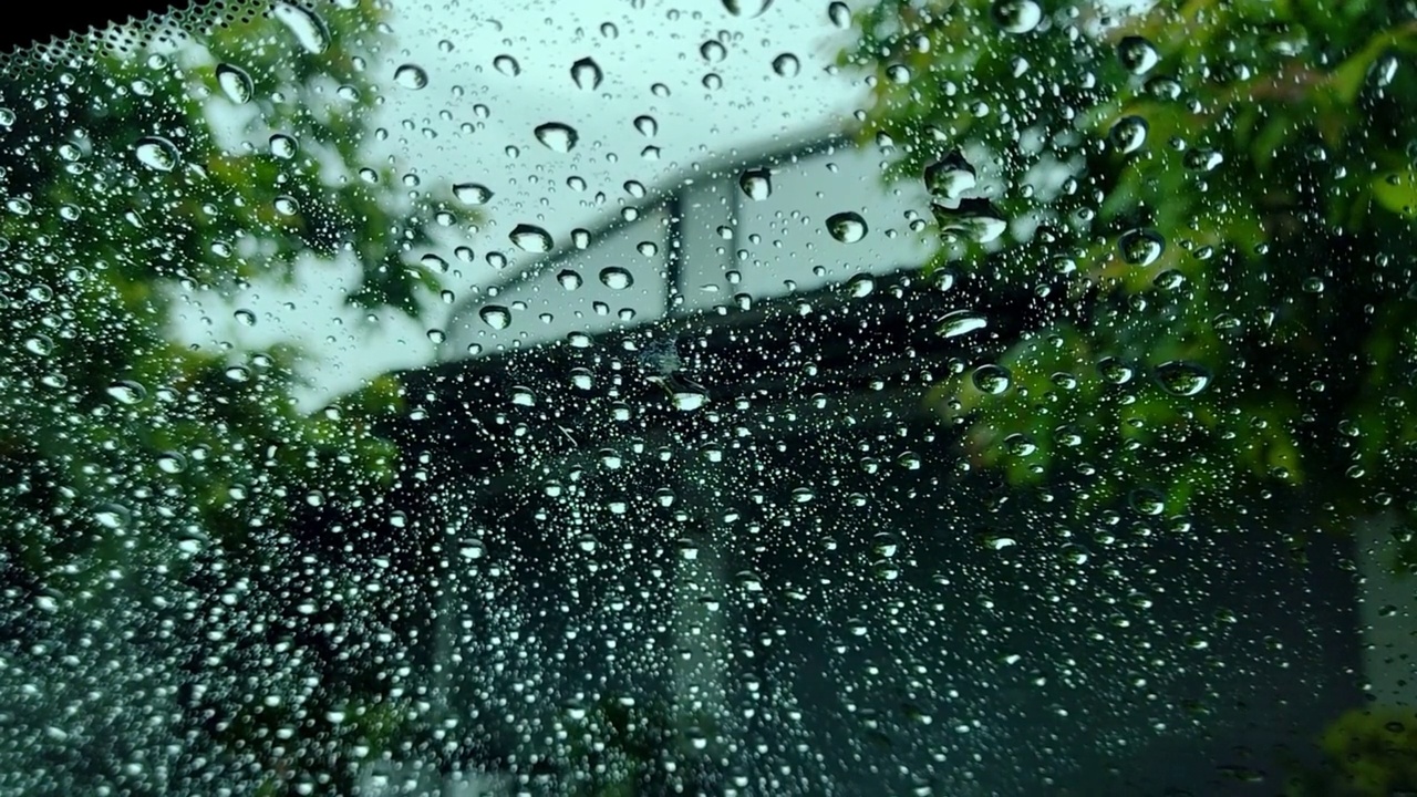 雨点和模糊离焦灯后面的雨点在草车。视频素材