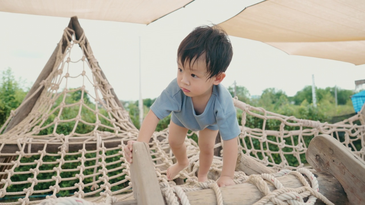 亚洲男孩在操场上爬绳子视频素材