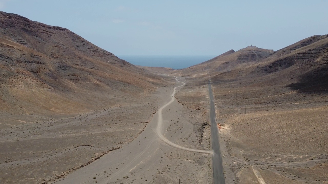 鸟瞰图，沿着海岸的火山景观和一条通往灯塔的道路。视频素材