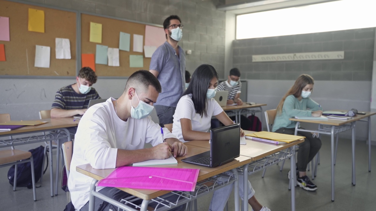 戴着口罩的老师走进教室，给高中的青少年学生讲解课程视频素材