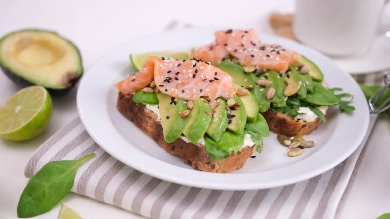 健康的早餐或零食——制作软奶酪、牛油果和三文鱼三明治视频素材