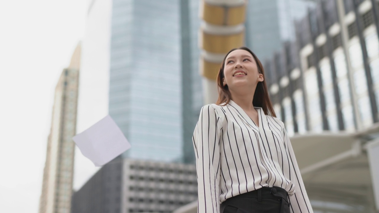 亚洲年轻漂亮的女商人在商业区把一堆文件纸扔向空中视频素材