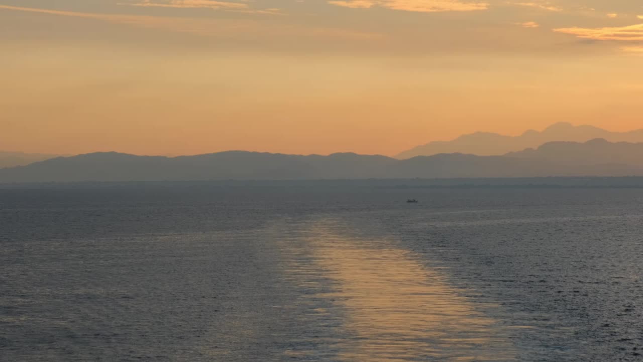 平静海面上令人惊叹的美丽日出。黄色的太阳从海上和山上升起，太阳的路径在水上。阳光和太阳光反射在水面上。金色的光，橙色和金色的蓝天视频素材