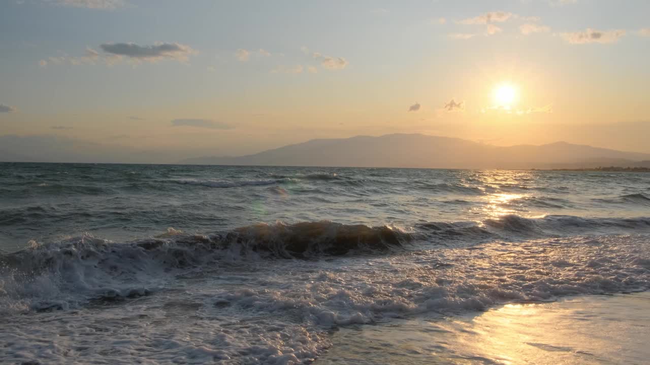 平静海面上美丽的日出。黄色的太阳升起在海和山之上，太阳的路径在水上。阳光和太阳光反射在水面上。金色的光，橙色和金蓝色的天空视频素材