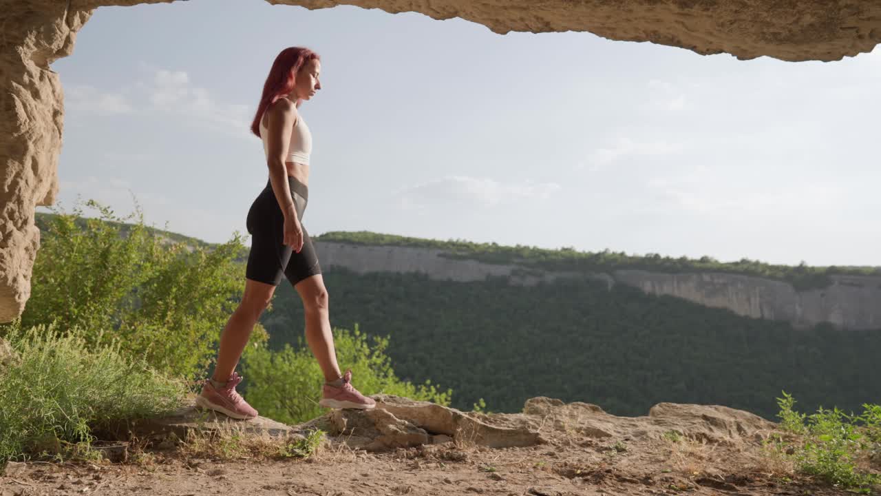 穿着运动服的苗条女子旅行者穿过洞穴走向出口视频素材