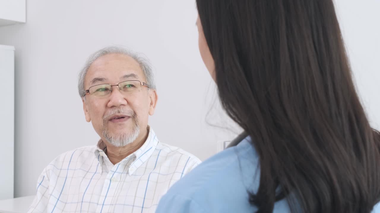 年长的男性病人坐在轮椅上与支持和帮助精神和健康护理的年轻女性护理人员交谈。视频素材