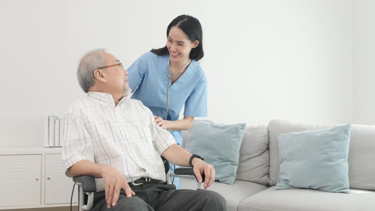 老年男性患者坐在轮椅上，由年轻女性护理人员支持和协助，保健理念。视频素材