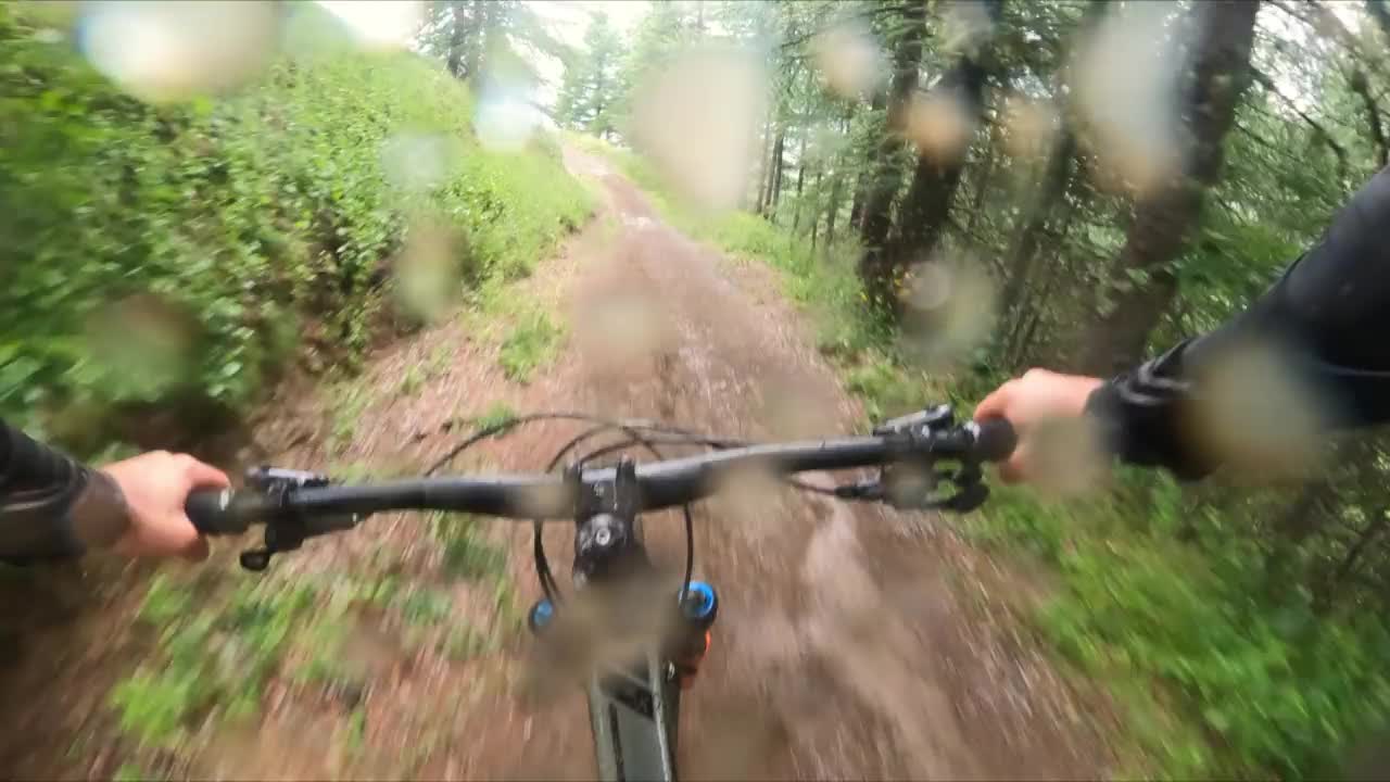 在下雨的天气里，骑MTB的人快速穿过森林，冲下山坡视频素材