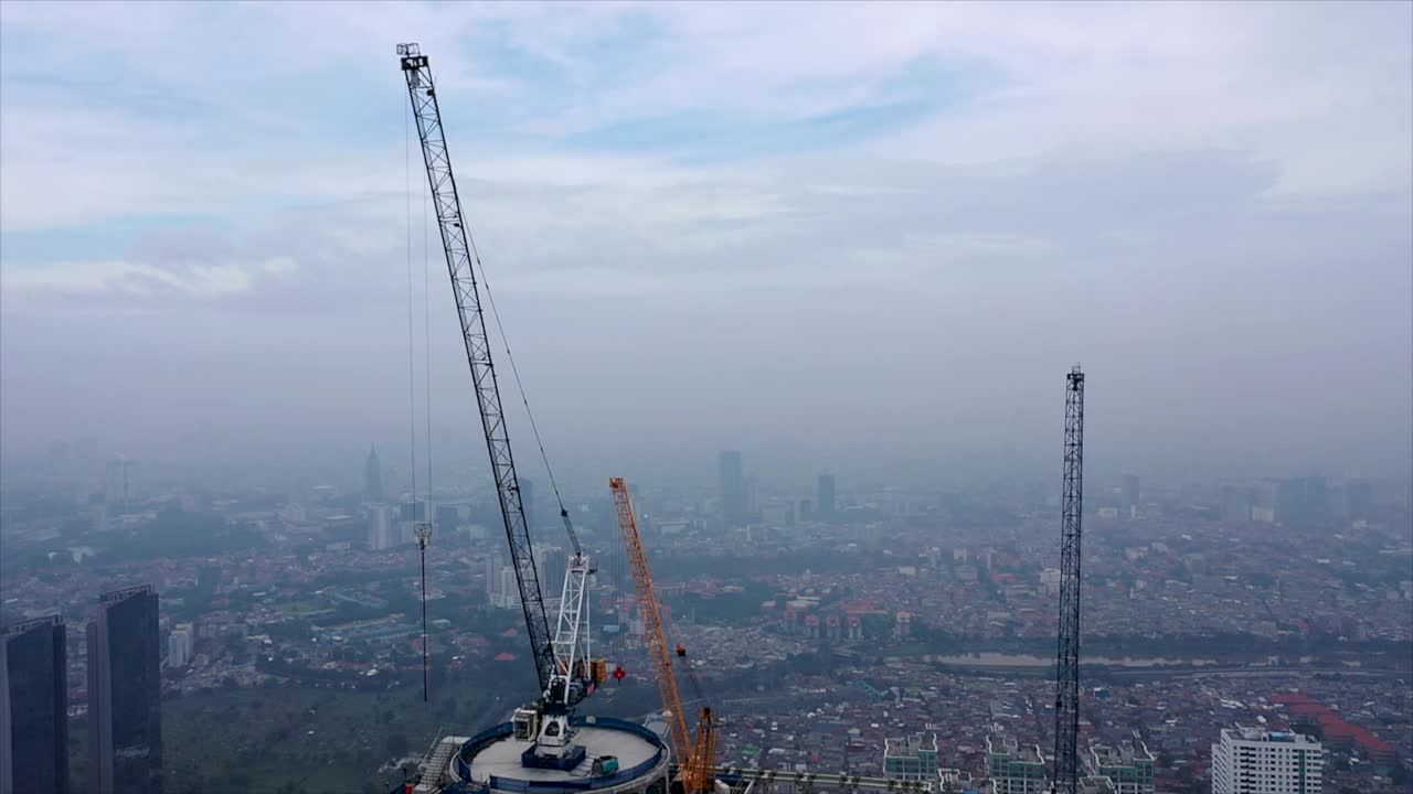 飞越建筑工地，担任建筑人员，施工人员工作，建造房屋。空中飞越一个新建建筑开发现场，高空塔式起重机正在建设房地产视频素材