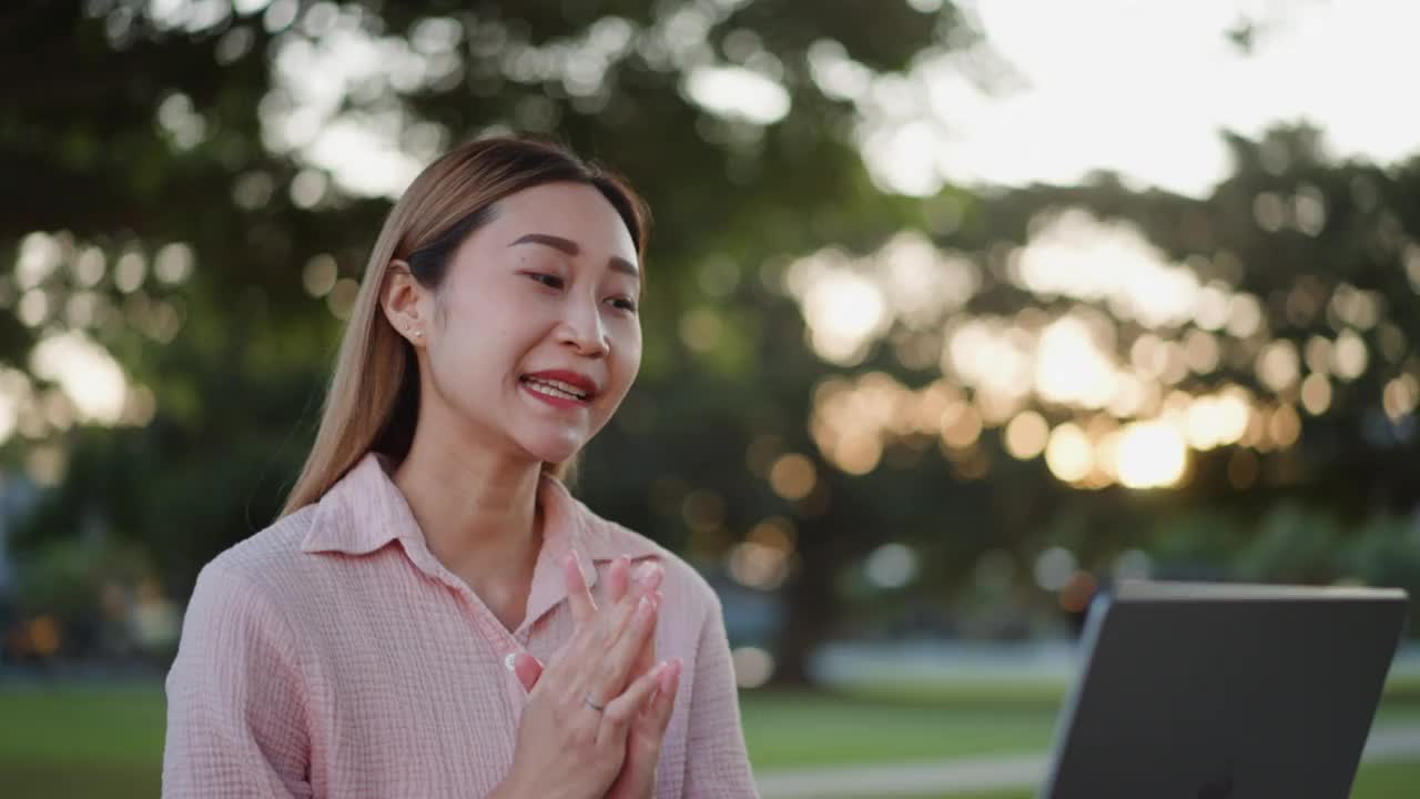 年轻的亚裔女大学生在公园户外使用笔记本电脑进行在线学习视频素材