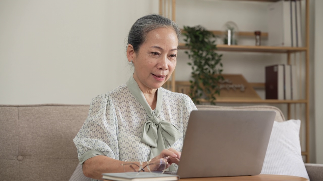 成熟的亚洲女性在家里使用笔记本电脑进行在线社区。视频素材