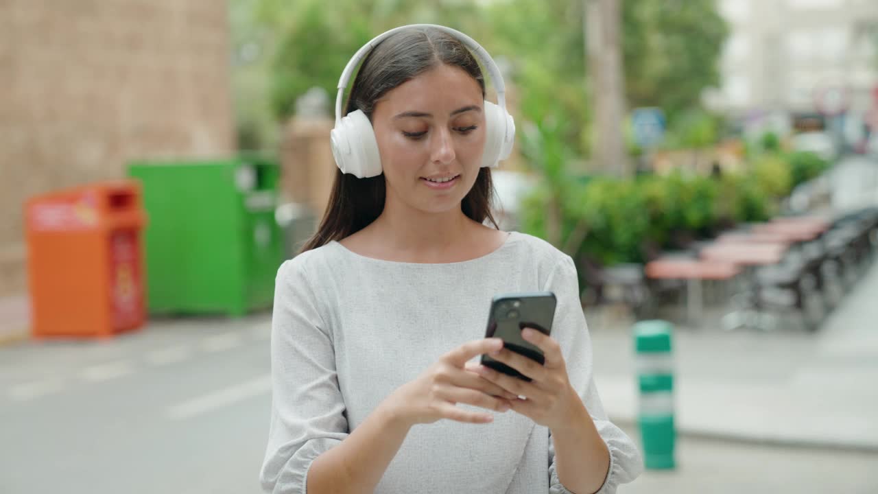 年轻美丽的西班牙女人在街上听音乐跳舞视频素材