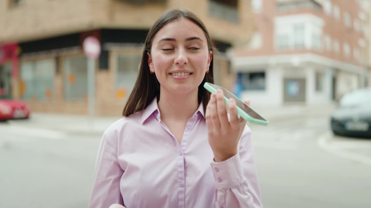 年轻的西班牙妇女微笑着自信地在街上用智能手机说话视频素材