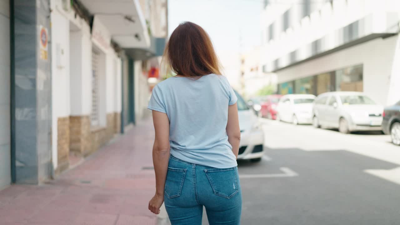 年轻女子微笑着，自信地站在街上，双臂交叉视频素材