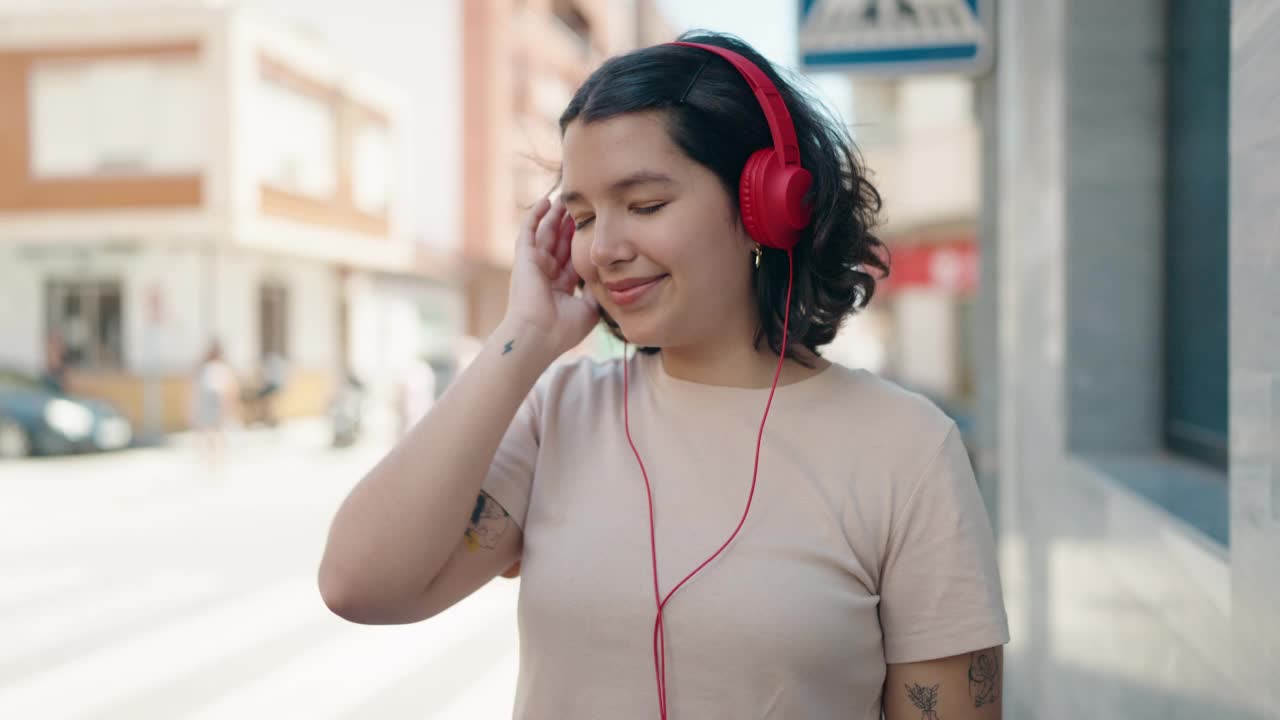 年轻女子微笑着，自信地听着音乐，在街上跳舞视频素材