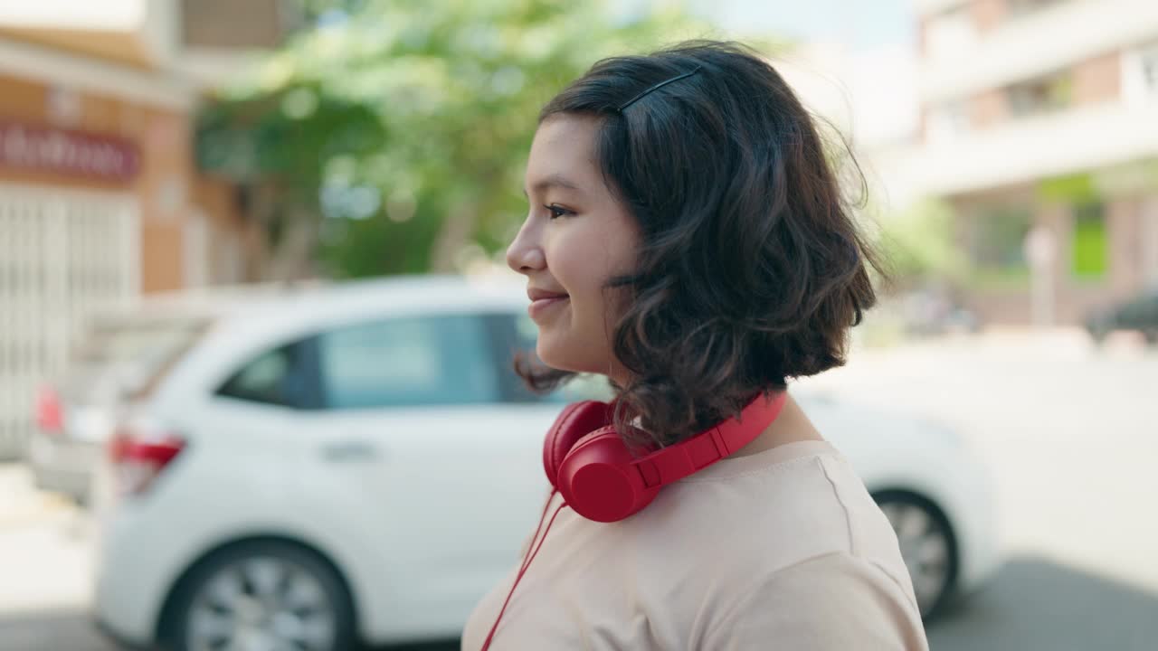 年轻女子微笑着，自信地听着音乐，在街上跳舞视频素材