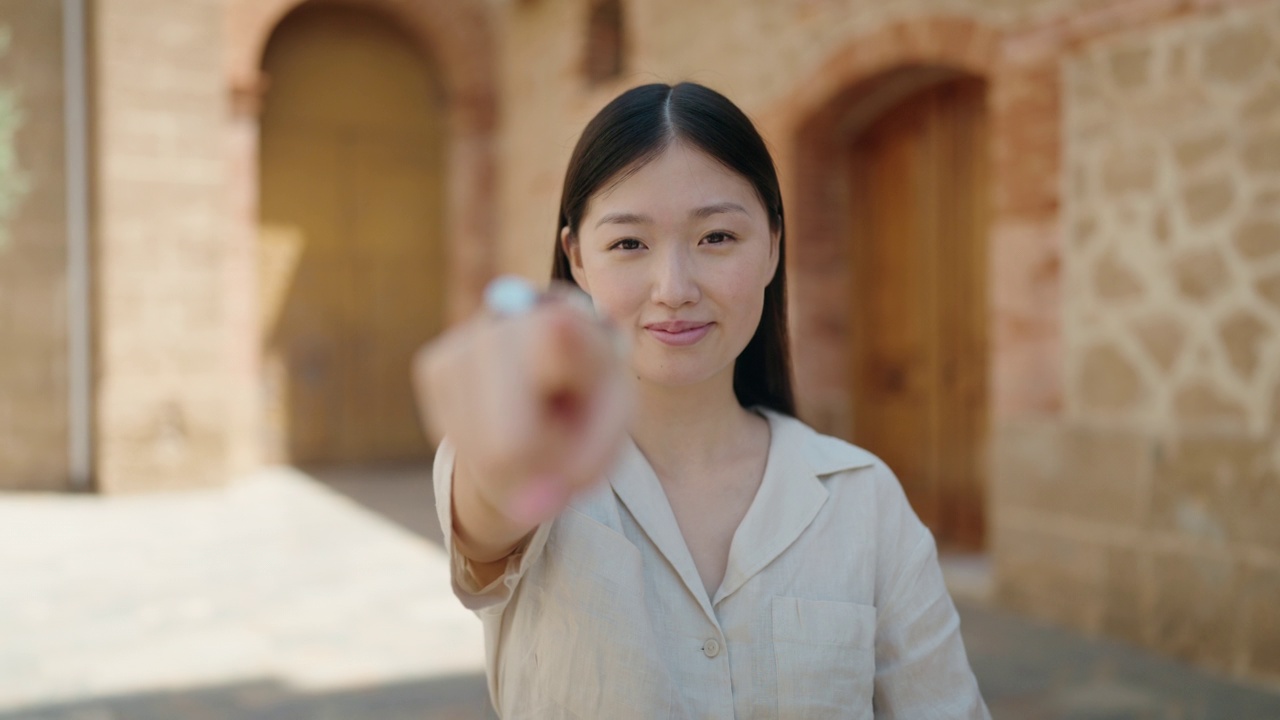 中国妇女微笑着自信地在街上用手做着走过来的手势视频素材