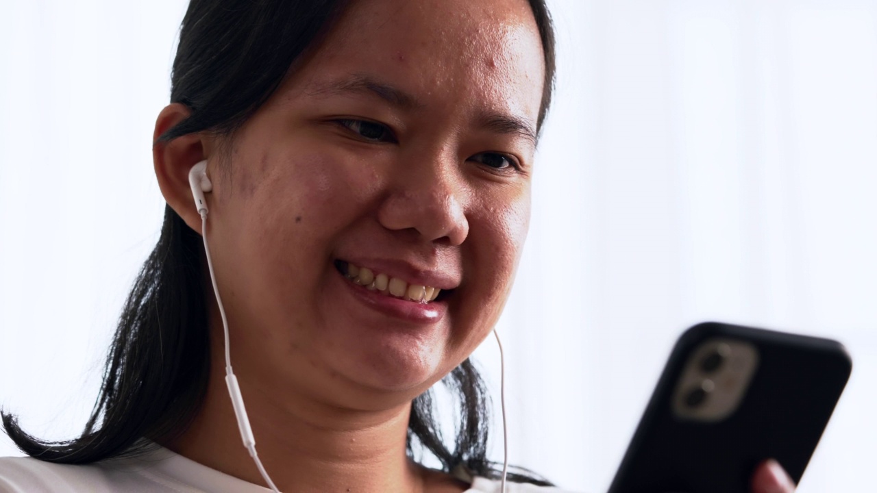 快乐的女人戴着耳机，喜欢用智能手机听音乐视频素材