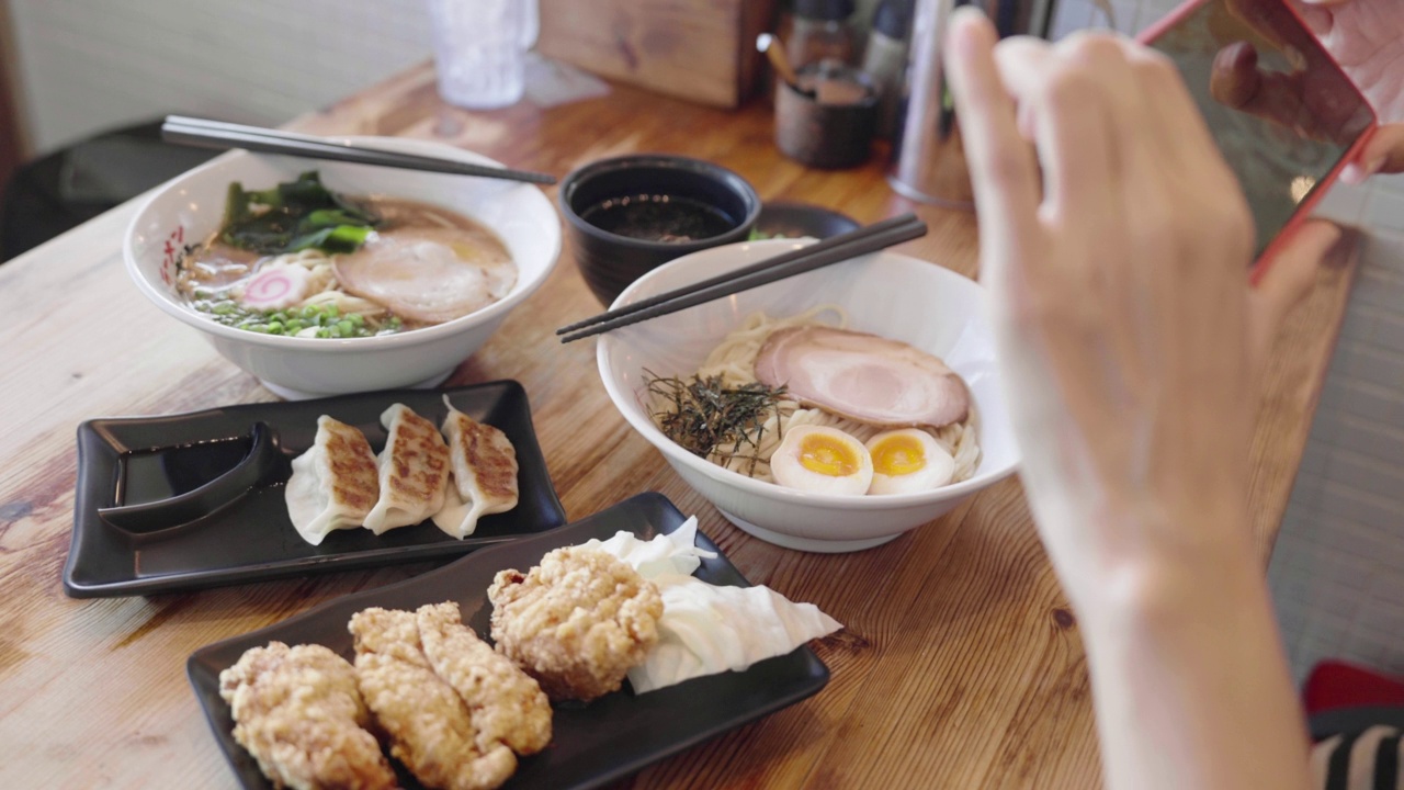 亚洲妇女在日本餐厅用手机拍拉面和日本食物视频素材