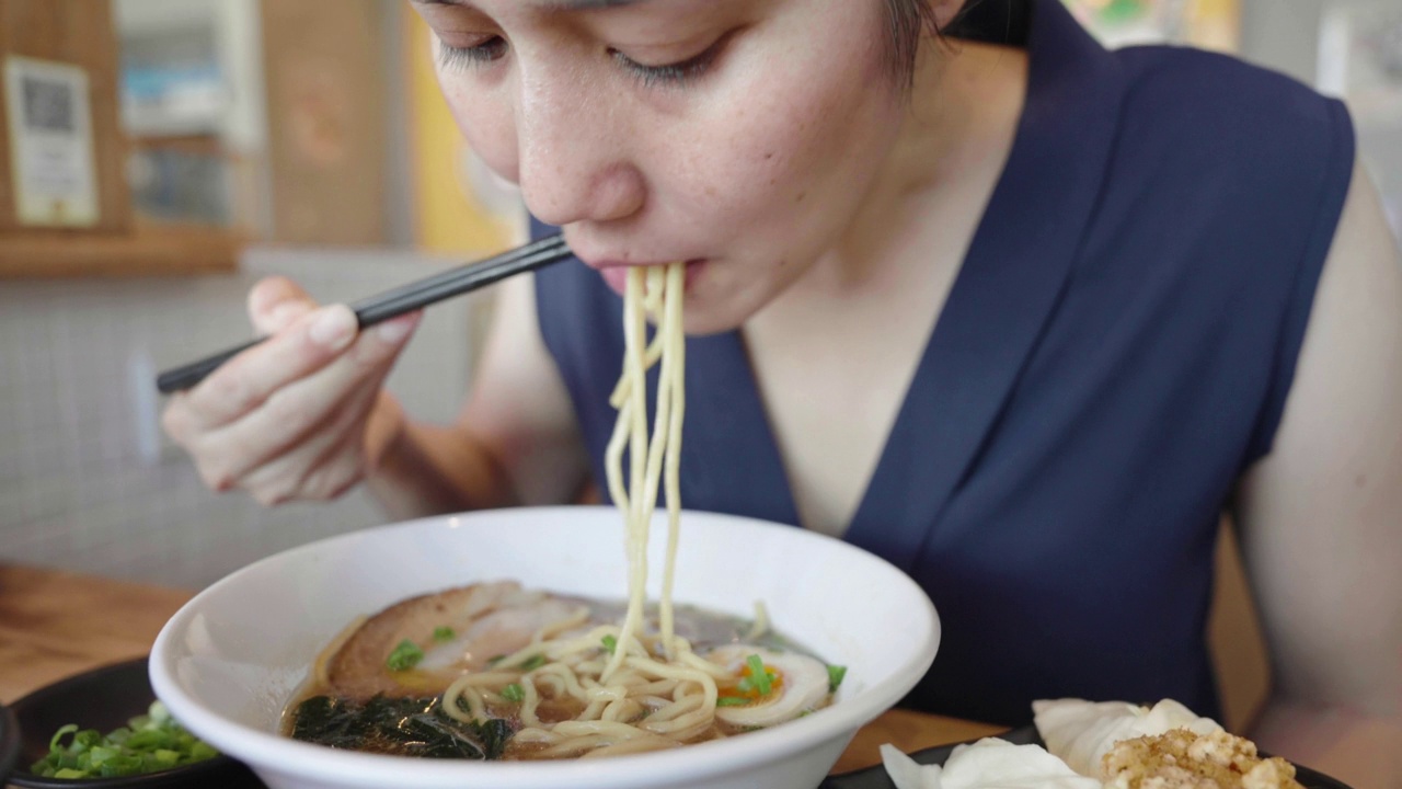 亚洲妇女在日本餐厅用筷子吃日式拉面视频素材