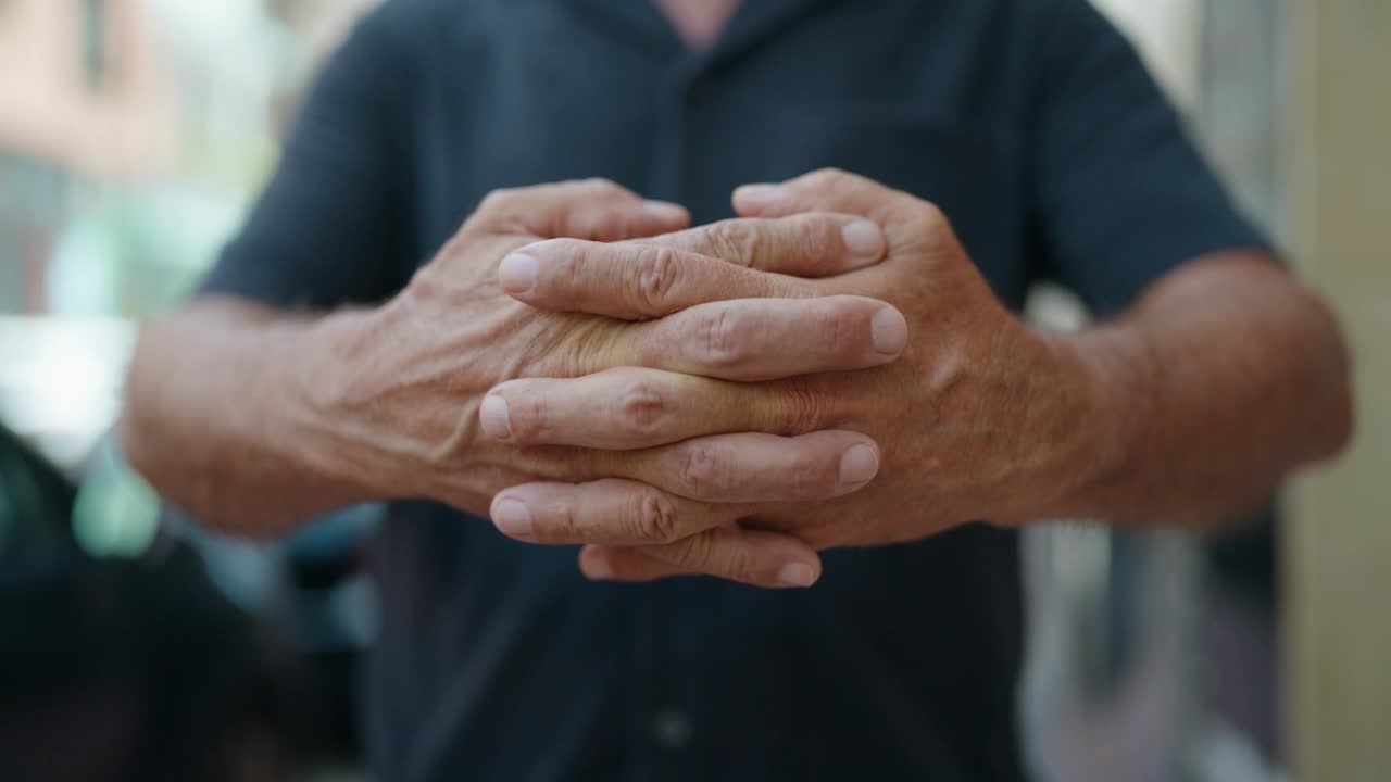 中年男子微笑着自信地站在街上，手握在一起视频素材