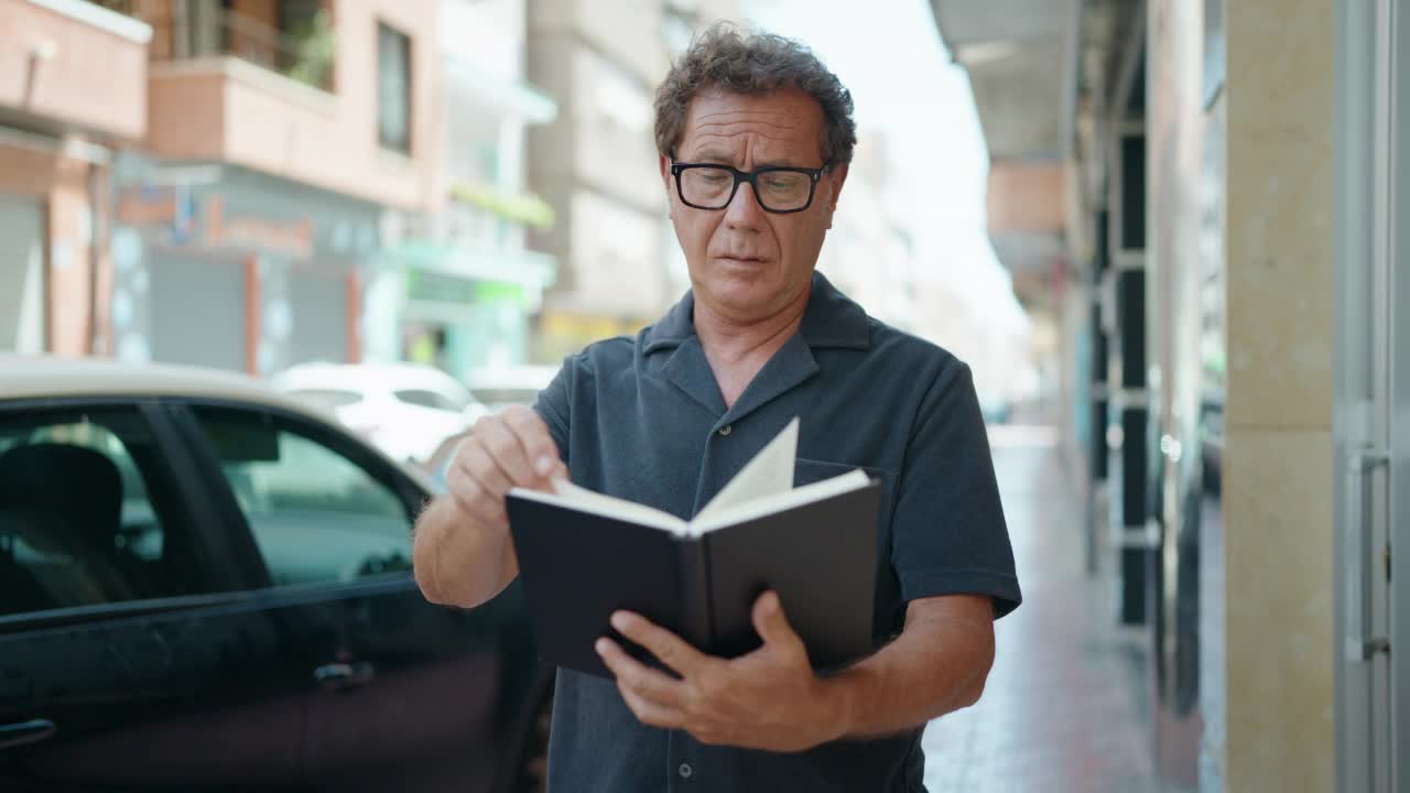 中年男子在街上悠闲地看书视频素材