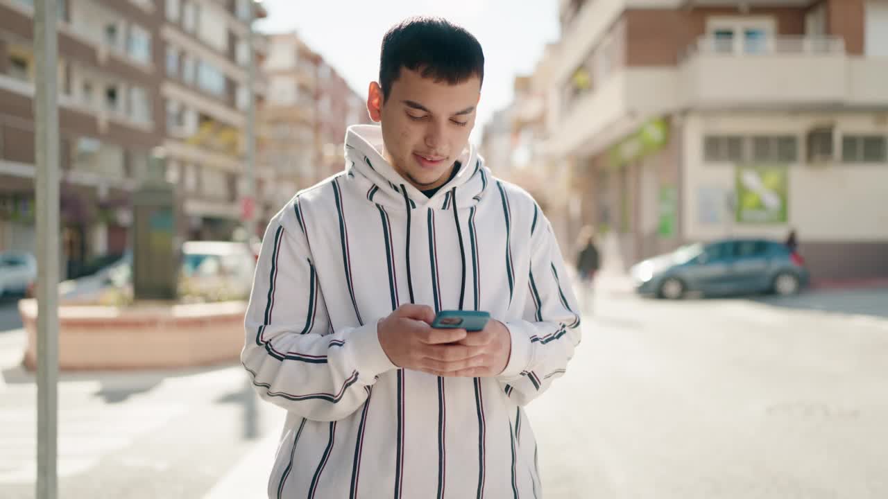 年轻男子自信地微笑着在街上使用智能手机视频素材