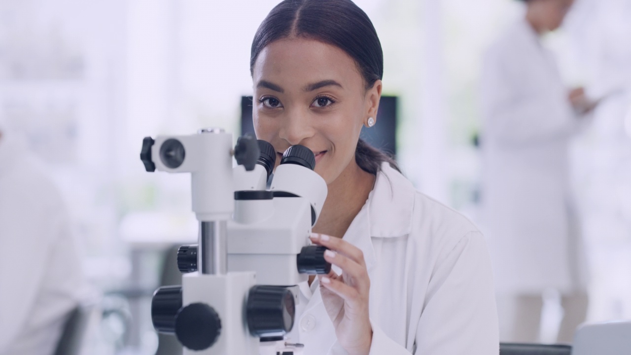 一位女科学家在实验室里使用显微镜的肖像。一名在科学的卫生机构为研究疫苗疗法分析样本的卫生保健专业人员，对生物学有热情视频素材