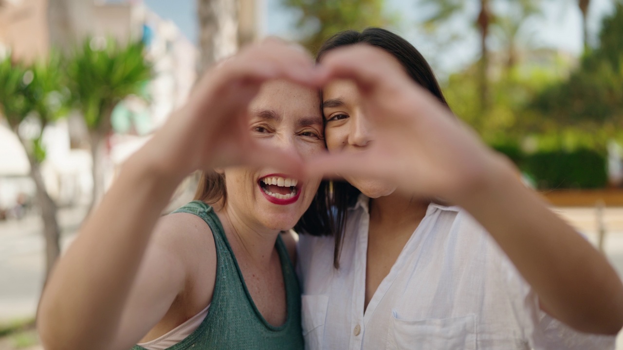 两个女人母女微笑着自信地用手在街上做着心的手势视频素材